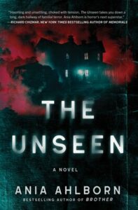 Cover of The Unseen shows a house with windows lit at night with pink smoke billowing around it.