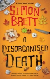 Cover shows a scattering of leaves, crumpled papers, a cardboard box, and a knife against a yellow background 