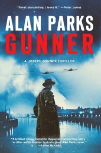Cover of Gunner shows a man in a long coat standing by a river lined by buildings with warplanes flying overhead through a cloudy sky.