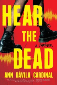 Cover of Hear the Dead shows a woman's feet shod in Doc Martins walking against a red background.